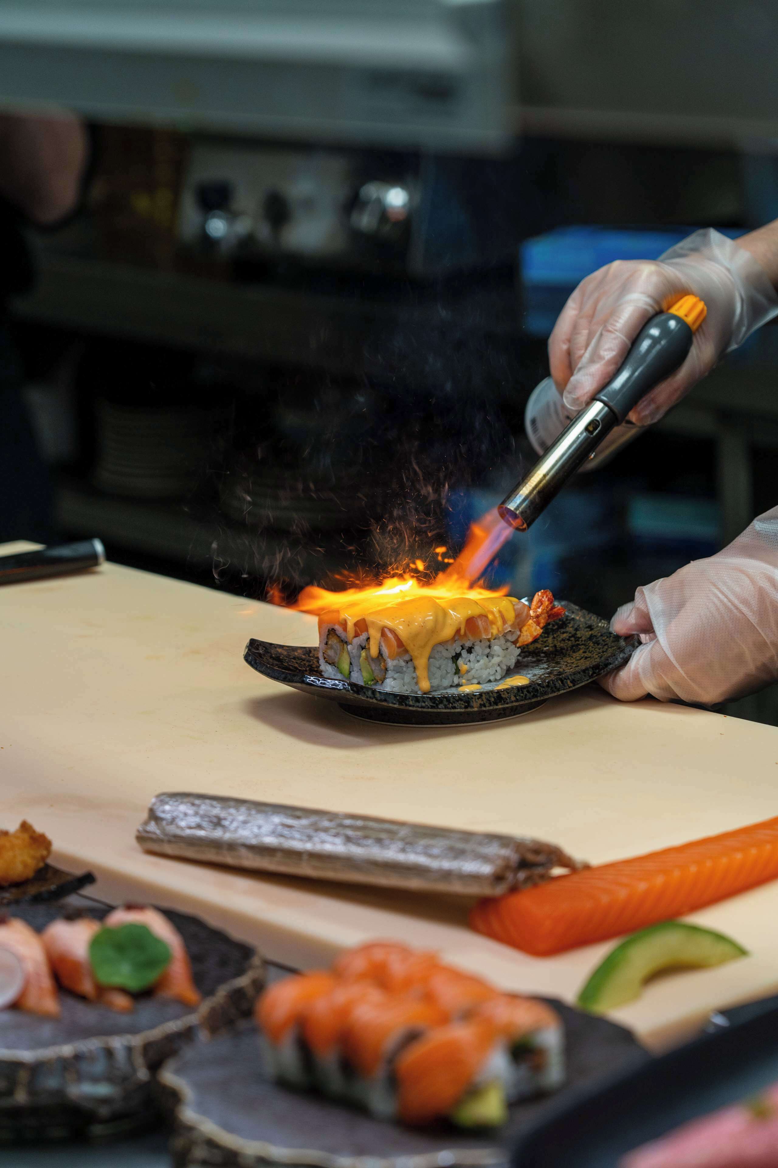Un plato de sushi siendo asado con un soplete.
