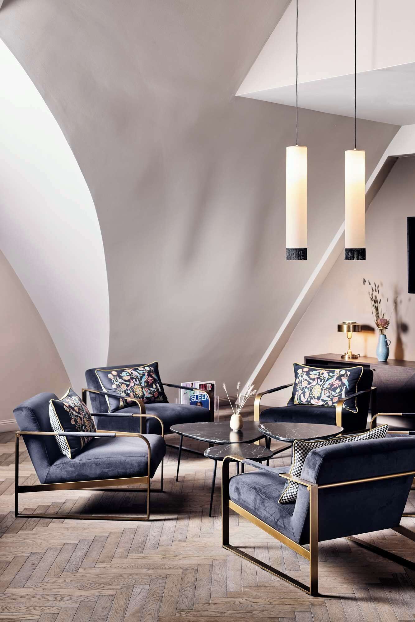 Ein moderner Lounge-Bereich mit dunkelblauen Polstersofas, einem runden Couchtisch und einer Kristallleuchter.