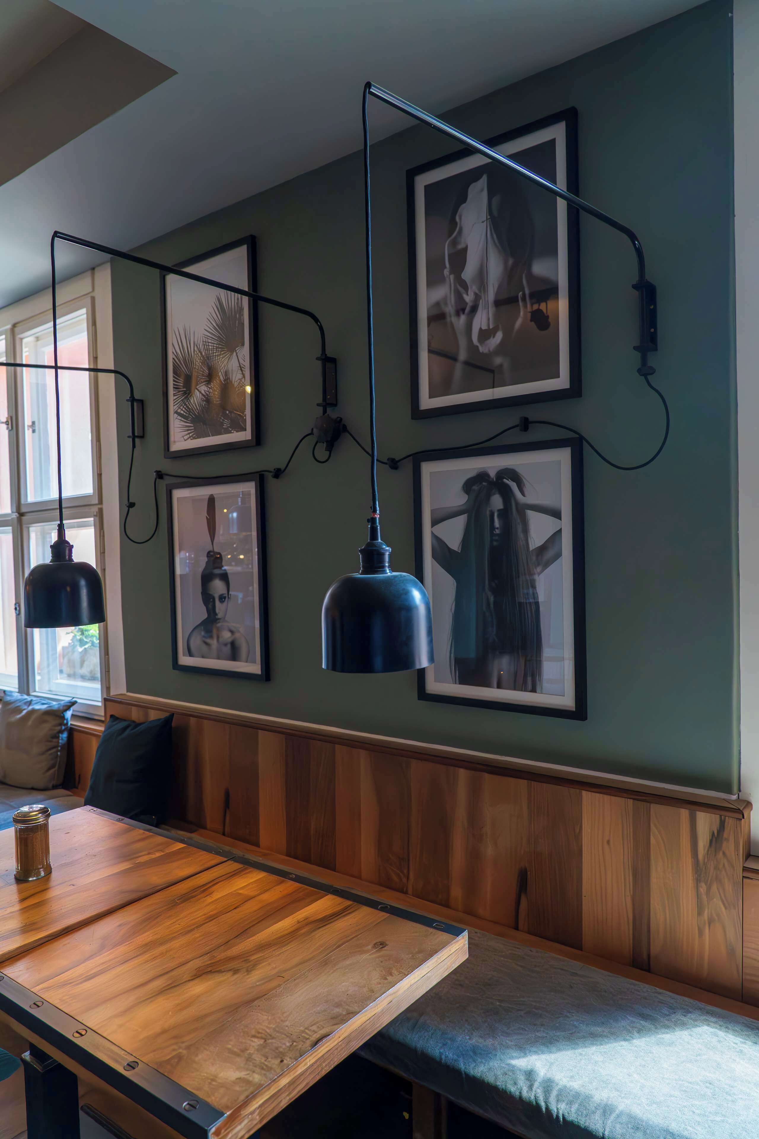 Un banco de madera con asiento acolchado, una mesa de madera y lámparas colgantes.