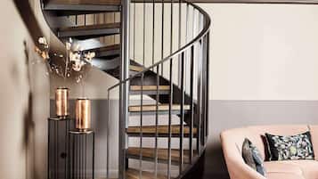 Una escalera espiral moderna con barandillas de metal y peldaños de madera, que conduce a un piso superior.