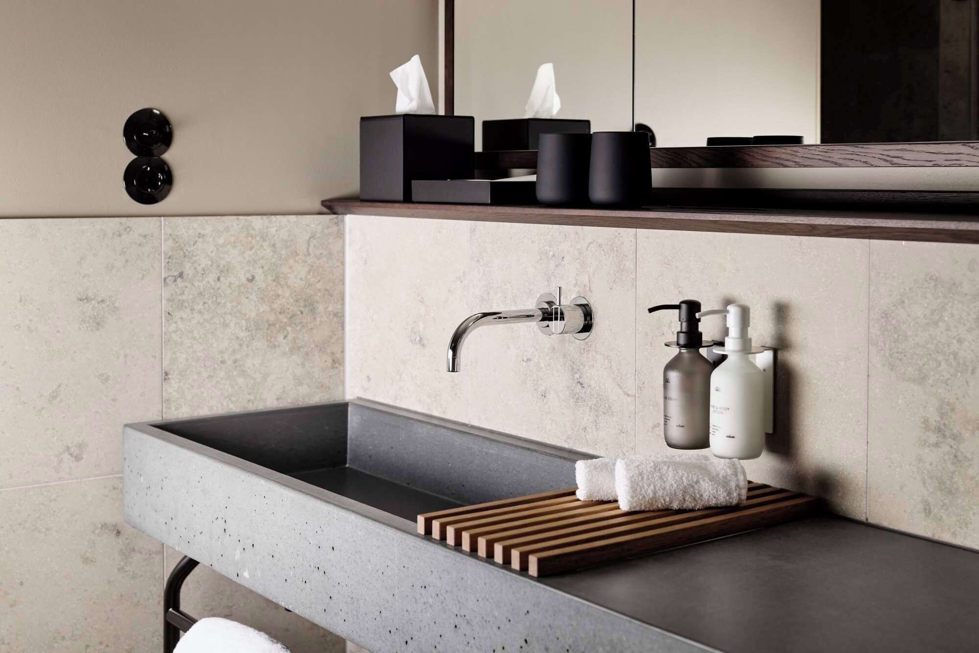 A modern bathroom with a grey sink, a towel rack, and a mirror.
