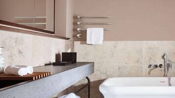 A modern bathroom with a large mirror, a bathtub, and a countertop with a soap dispenser and towel holder.
