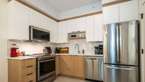 Una cocina moderna con armarios blancos, electrodomésticos de acero inoxidable y detalles de madera.
