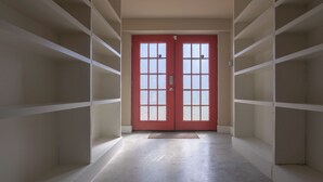 A hallway with a red door, white shelving units, and a doormat. - Gorgeous Guesthouse Near Amazing Downtown (San Antonio)