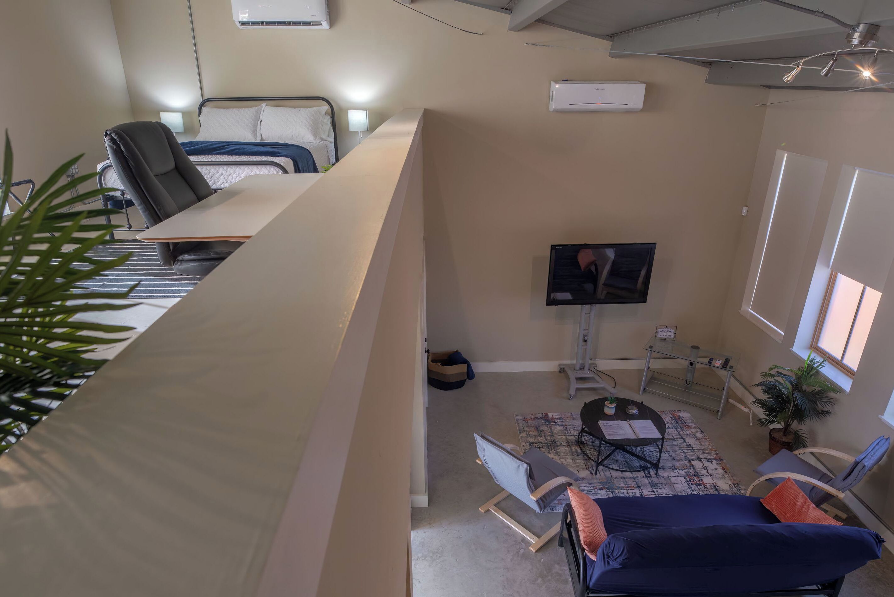 A hotel room with a bed, a desk, a chair, a TV, a small table, and a window.