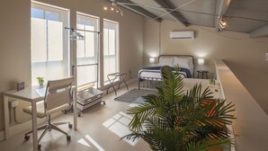 A modern bedroom with a bed, bedside table, lamp, and a large window. - Gorgeous Guesthouse Near Amazing Downtown (San Antonio)