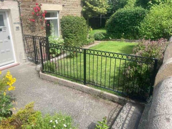 A residential property with a stone facade, a paved driveway, a well-maintained lawn, and a black metal fence. - Stunning Pet friendly Cottage in beautiful Weardale (Ireshopeburn)