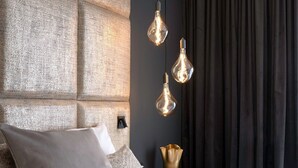 A modern bedroom with a large tufted headboard, a neatly made bed with a white comforter, and three hanging pendant lights. - THE Newsha Signature Home (Muelheim an der Ruhr)