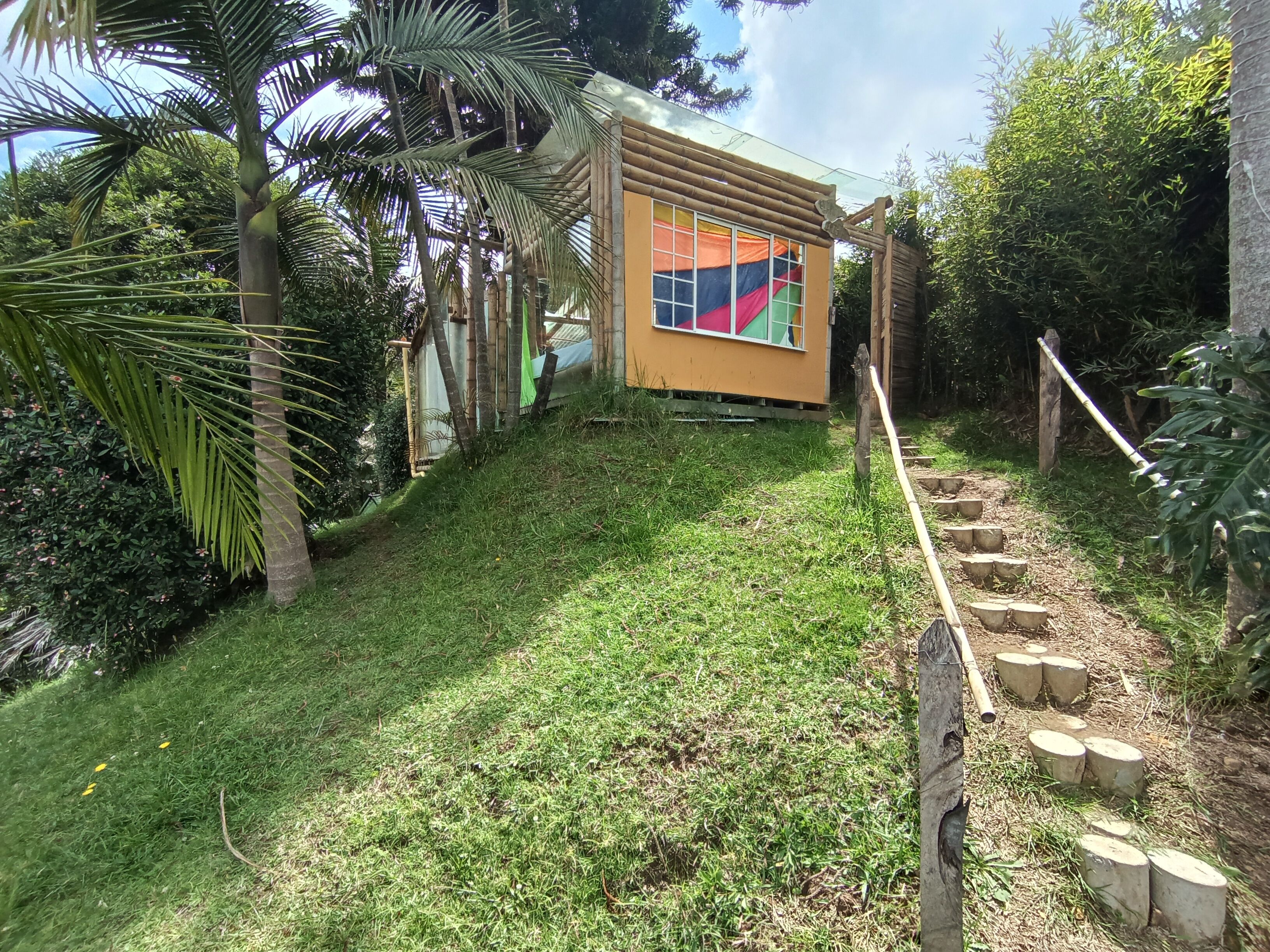 Un pequeño edificio de una sola planta con fachada amarilla y una ventana con cortinas coloridas.