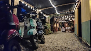 A covered outdoor area with scooters parked under string lights. - Biohotel Ecohouse (Guarne)