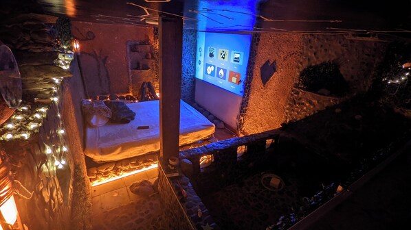A dimly lit room with a bed, a stone wall, and a small window. - Biohotel Ecohouse (Guarne)