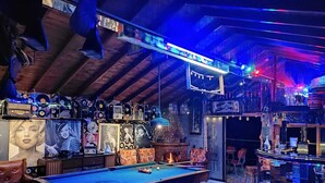 A pool table in a room with a wooden ceiling, bar area, and various framed pictures on the walls. - Biohotel Ecohouse (Guarne)