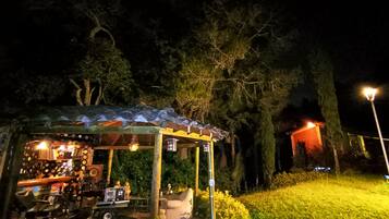 Una pequeña estructura al aire libre con un área de estar techada, una mesa con varios objetos y un elemento azul en el suelo.