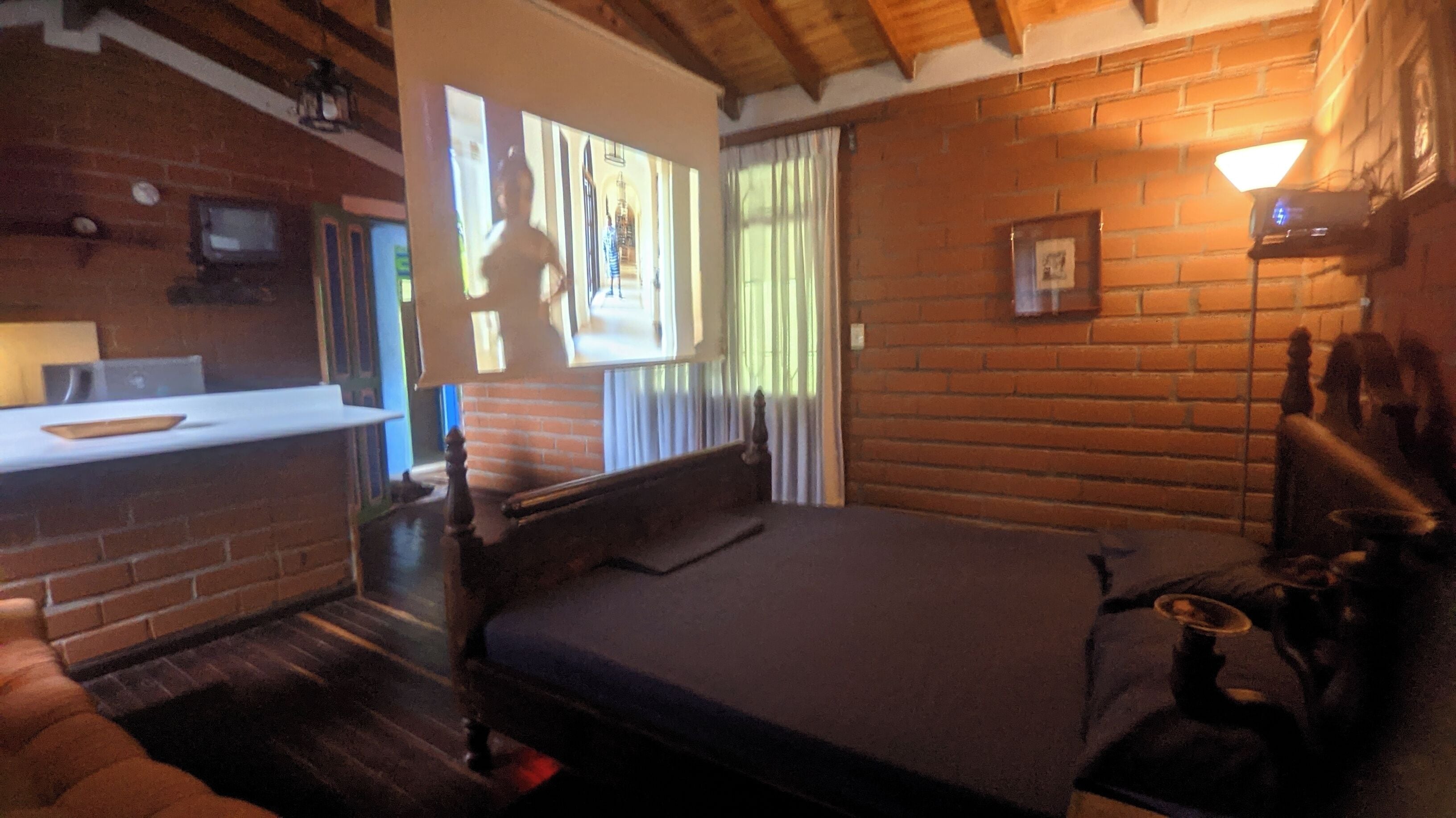 Une pièce comprenant un lit, une petite table, une chaise, un téléviseur et une fenêtre avec des rideaux.
