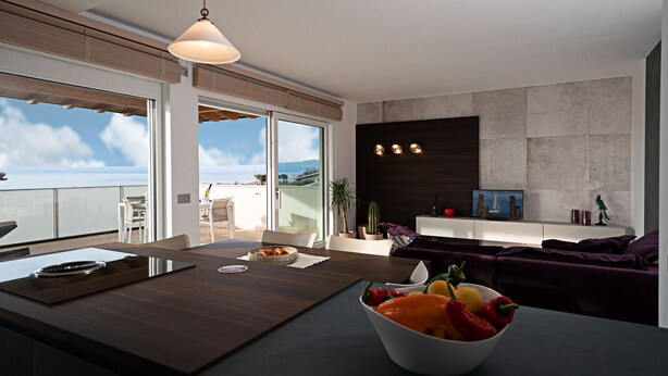 Een moderne keuken met een groot eiland, een eethoek met uitzicht en een zithoek met een bank en televisie.