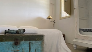 Une chambre à coucher avec un lit, une commode, une lampe et une fenêtre avec un miroir.