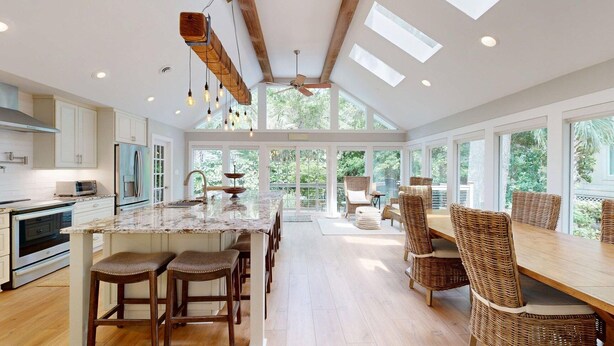 A spacious kitchen with a central island, bar stools, and a dining area with wicker chairs. - New to the Rental Market! (Hilton Head)