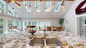 A spacious kitchen with a marble countertop, modern lighting, and large windows. - New to the Rental Market! (Hilton Head)