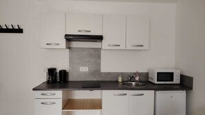 A modern kitchen with white cabinets, a stainless steel sink, a microwave, and a coffee maker.