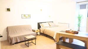 A bedroom with a bed, a sofa, a small table, and a radiator.