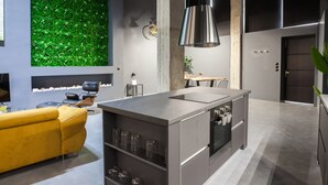 Een moderne keuken met een centraal eiland, een gele bank en een groene wand.