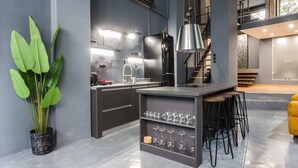 Een moderne keuken met een centraal eiland, barstoelen en een potplant.