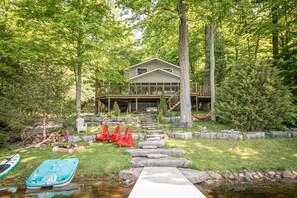Une maison avec une terrasse, un chemin de pierres et un petit ruisseau.