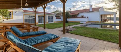 Un espacio al aire libre cubierto con sillones de madera y una piscina.