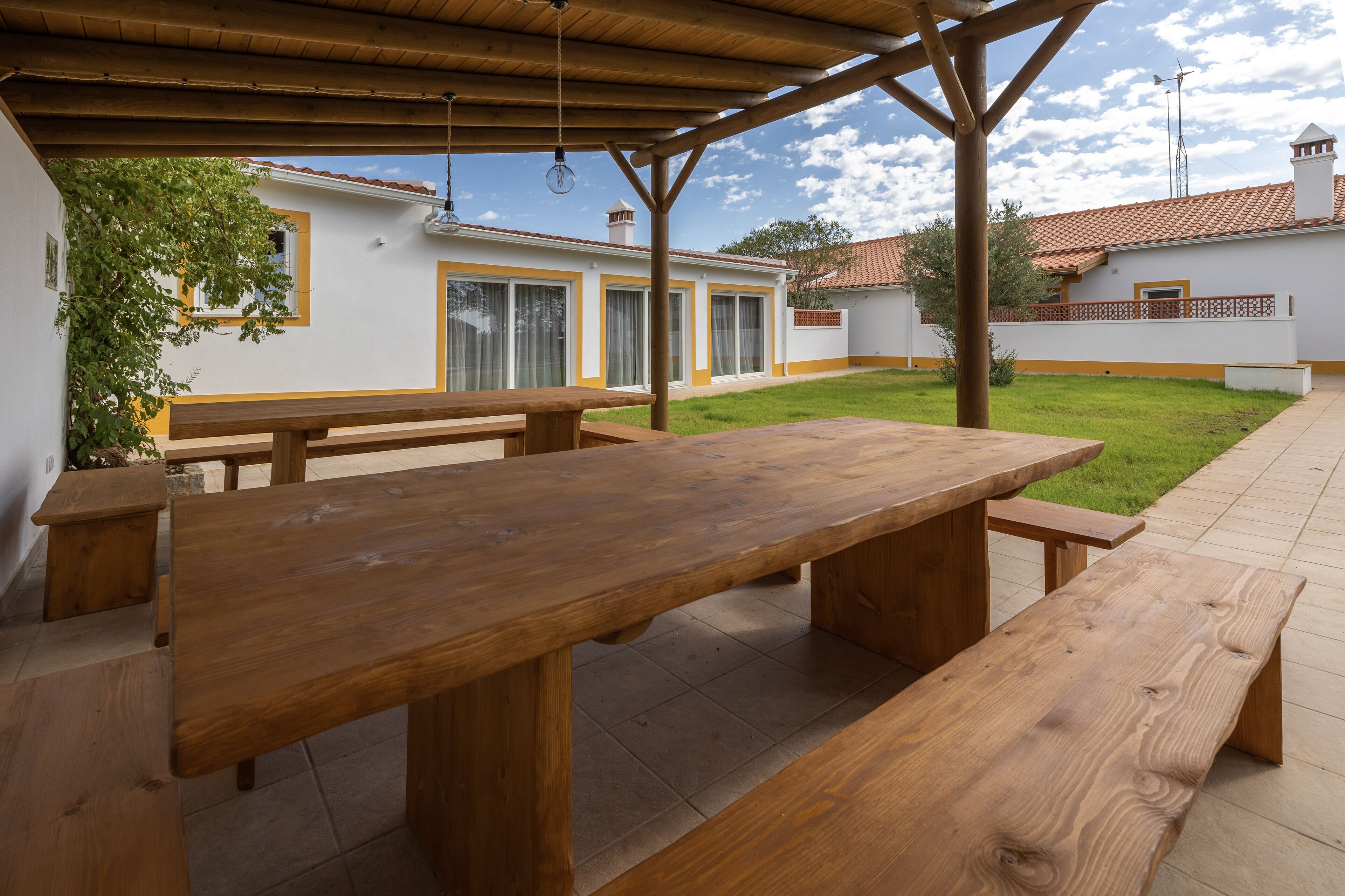 Un patio exterior con bancos de madera y una zona cubierta.