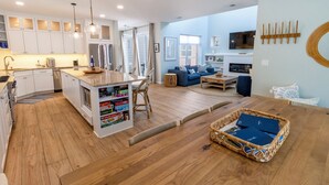A modern kitchen with white cabinets, a central island, and a dining area with a wooden table and chairs. - Bright, Airy Beachwalk Resort w/Golf Cart (Michigan City)