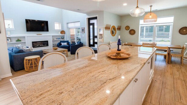 A modern kitchen with a large island, dining area, and a living room with a sofa and TV. - Bright, Airy Beachwalk Resort w/Golf Cart (Michigan City)