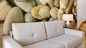 Un sofá en una habitación con pared de piedra de fondo.