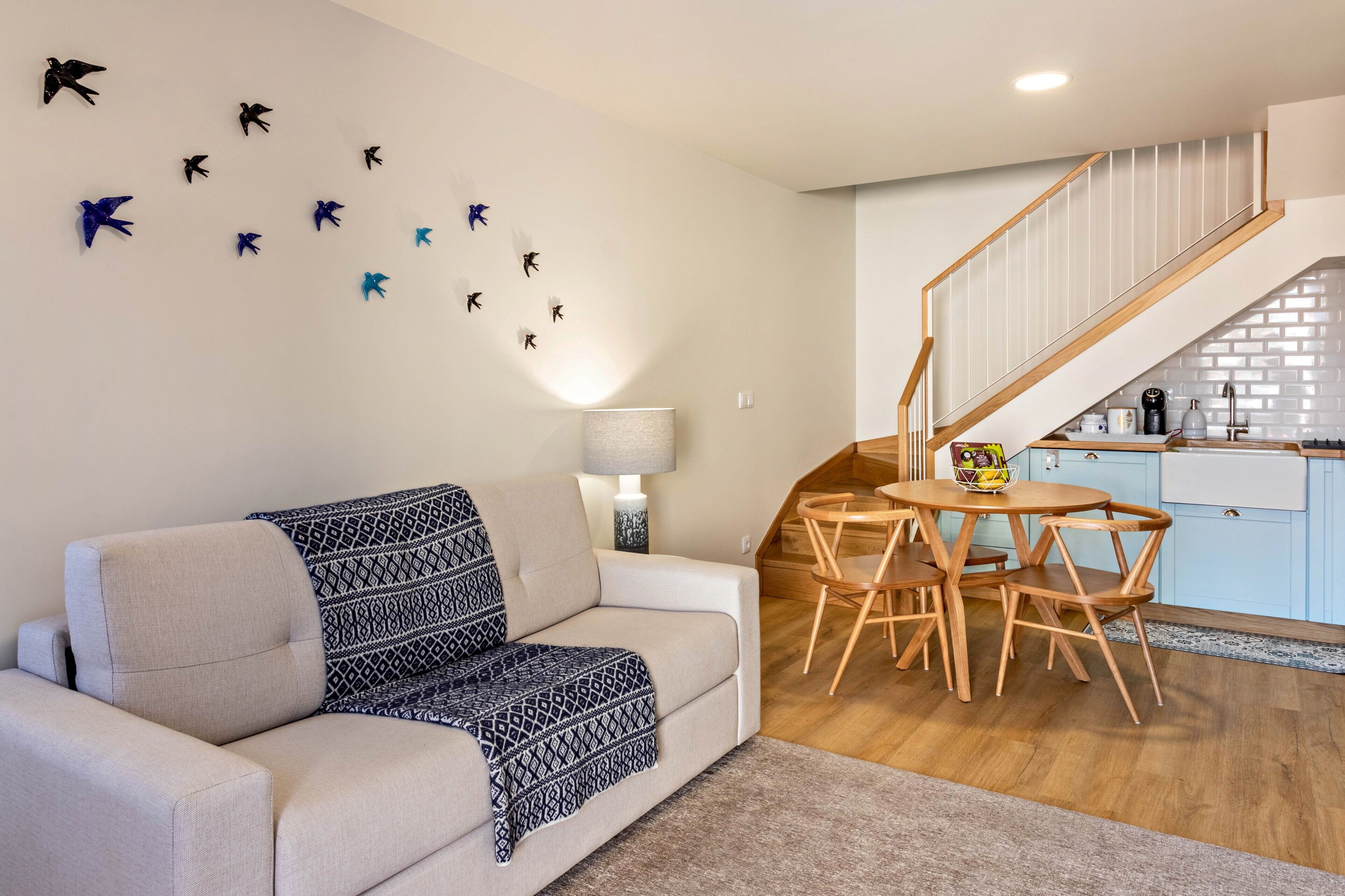 A living room with a sofa, a coffee table, a lamp, and a staircase leading to a kitchen.