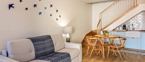 A living room with a sofa, a coffee table, a lamp, and a staircase leading to a kitchen.