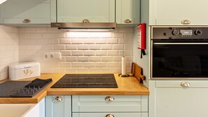 A kitchen with light blue cabinets, a white tiled backsplash, a built-in oven, and a toaster. - Holiday Home "Casa das Andorinhas" with Private Terrace & Wi-Fi (Câmara de Lobos)