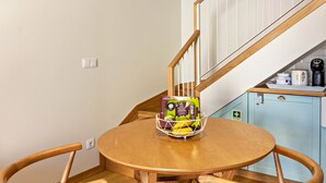 A wooden dining table with chairs, a basket of items, and a staircase in the background. - Holiday Home "Casa das Andorinhas" with Private Terrace & Wi-Fi (Câmara de Lobos)
