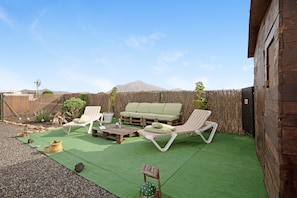 Eine Terrasse mit Gartenmöbeln, einem Holzzaun und einem Berg im Hintergrund.