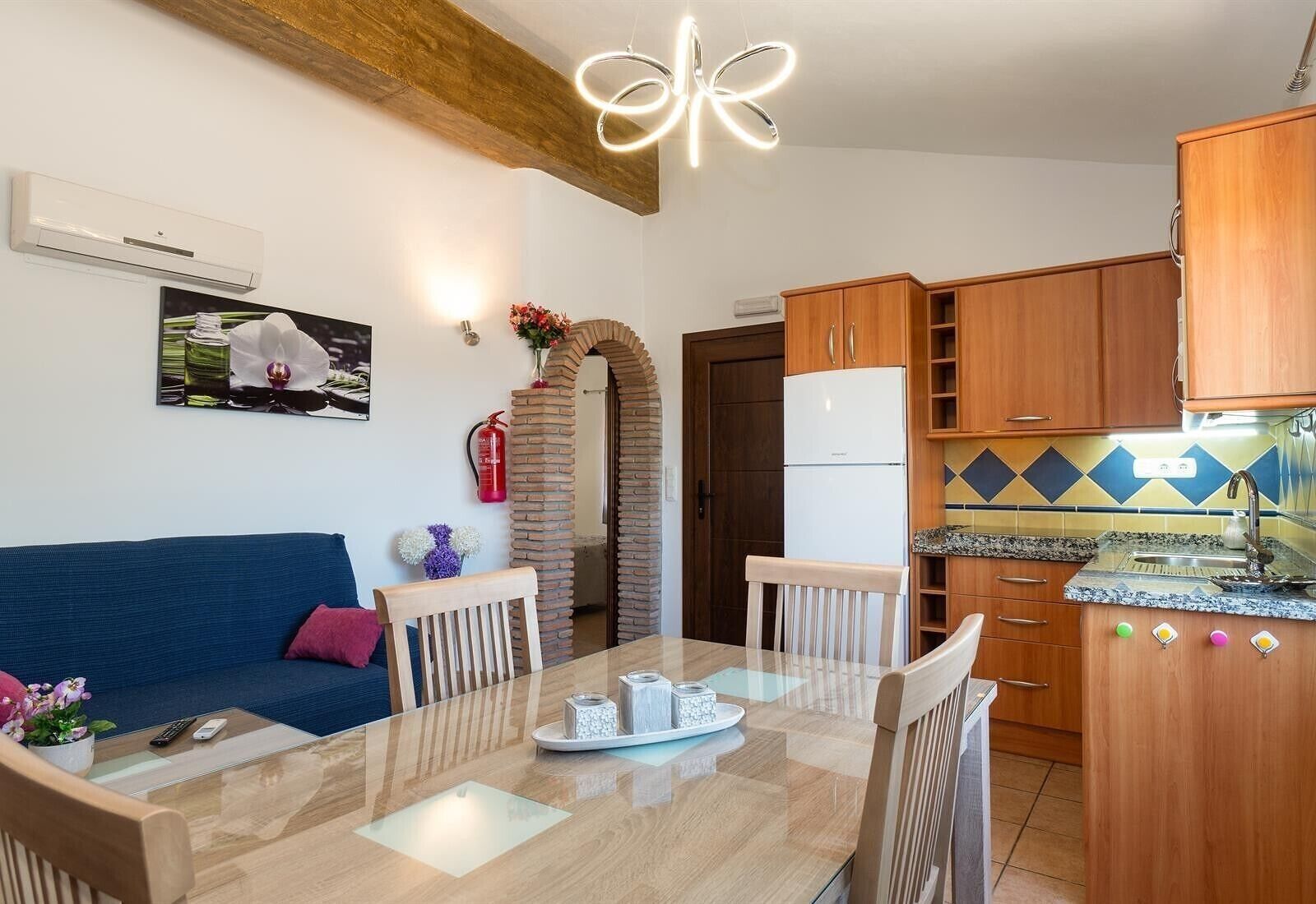A compact living space with a dining area, kitchenette, and a blue sofa.