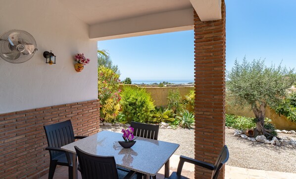 A patio with a table and chairs, a wall-mounted fan, a lantern, and a flower pot.