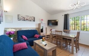Un salon comprenant un canapé, une table basse, un téléviseur et un coin repas avec des chaises et une table.