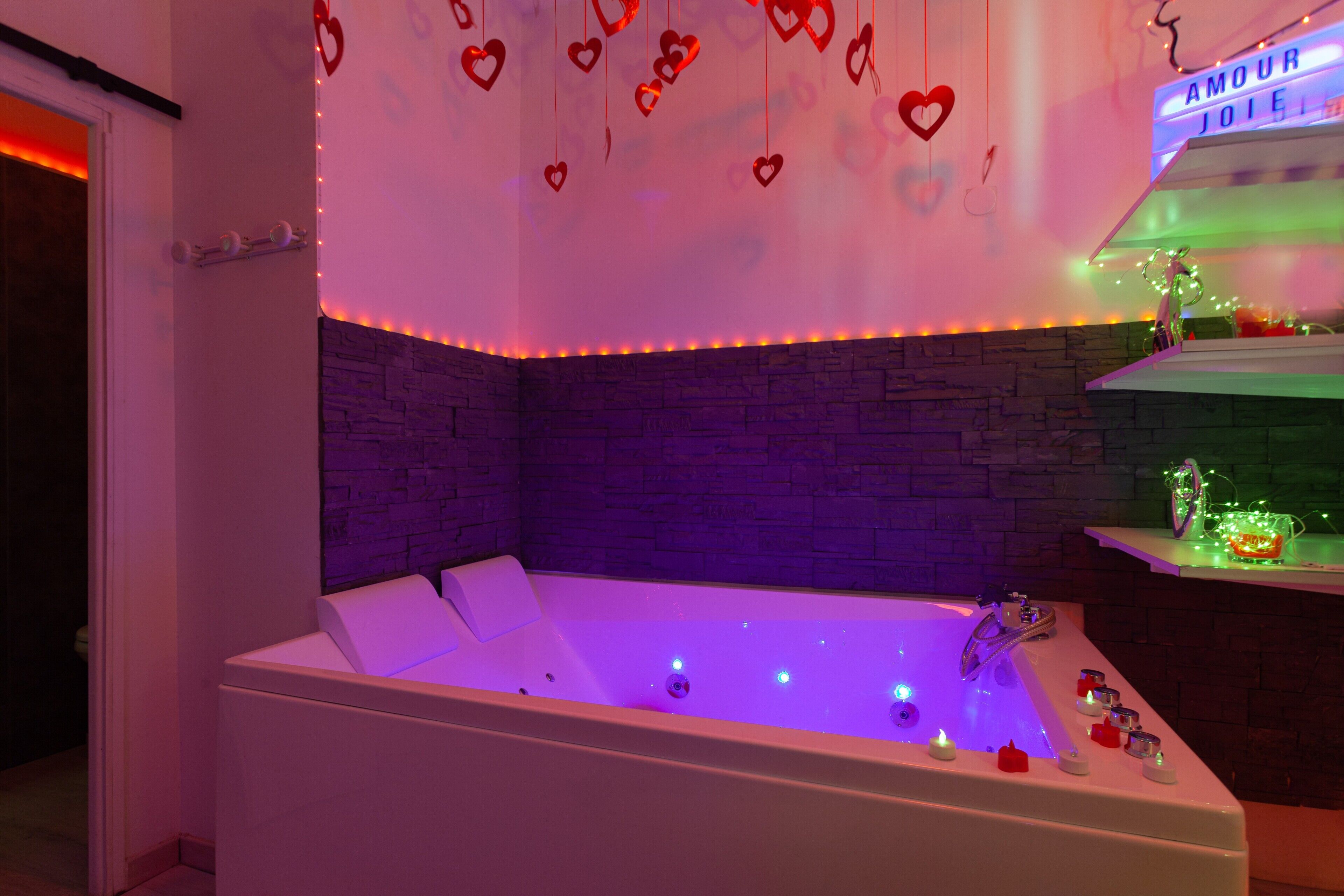 Une salle de bain moderne avec une baignoire, des décorations en forme de cœur et un néon.