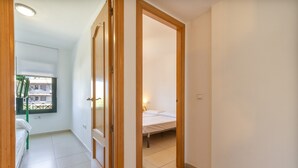 Ein Zimmer mit einem Bett, einem Fenster mit Blick und einer Tür zu einem anderen Raum.