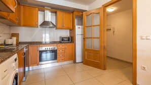 Eine Küche mit Holzschränken, einer Mikrowelle, einem Backofen und einem Kühlschrank.