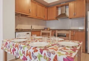 A kitchen with wooden cabinets, a microwave, and a dining table set with plates and glasses.