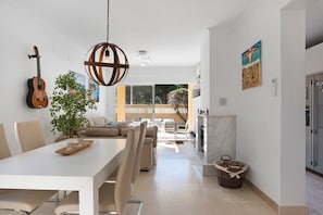 A modern kitchen with a dining area, a hanging guitar, and a large window.