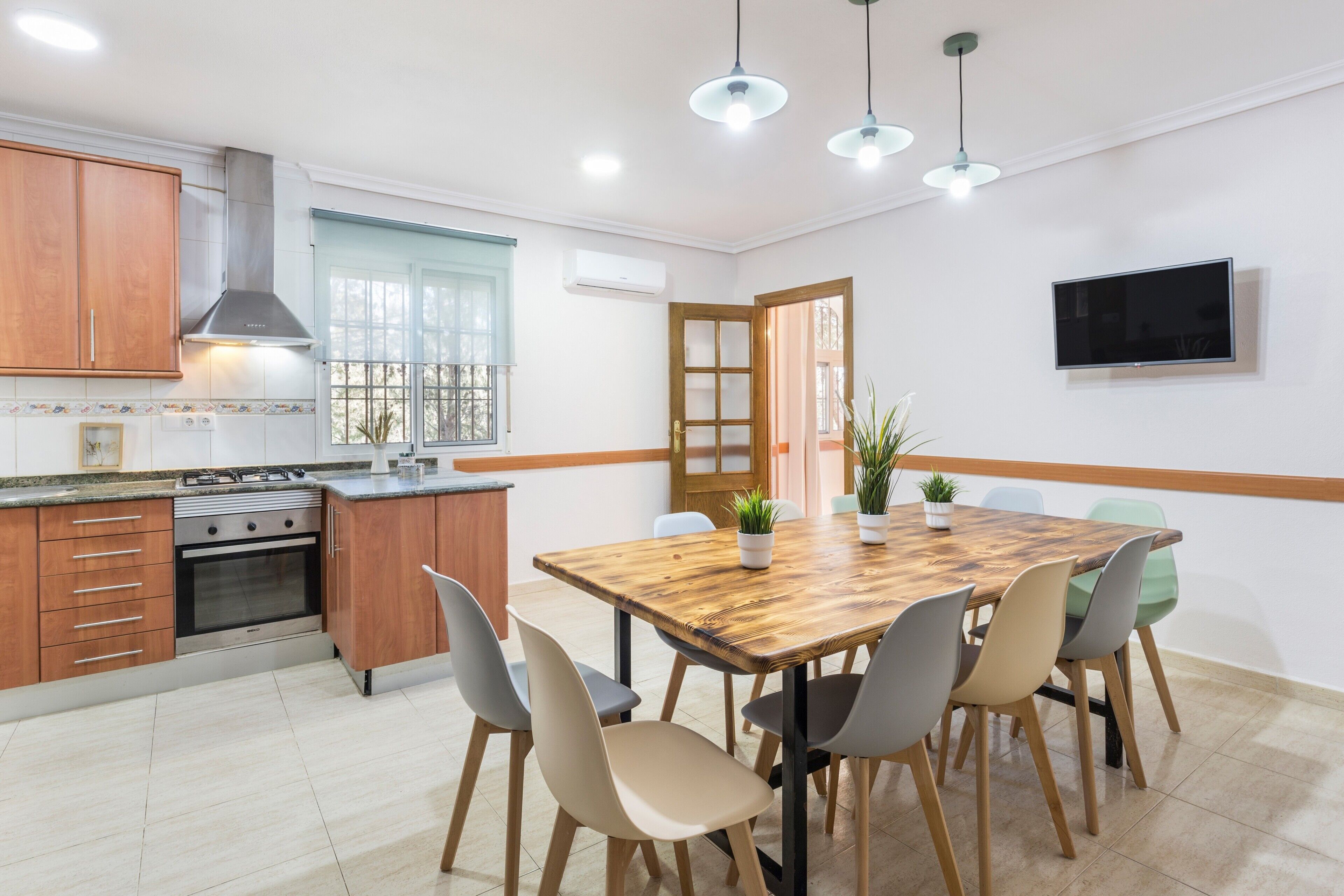 Una cocina moderna con armarios de madera, horno empotrado y comedor con mesa y sillas de madera.