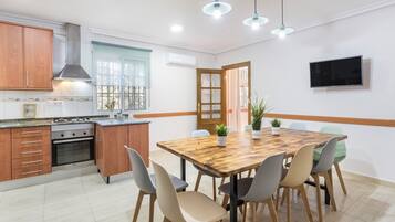 Una cocina moderna con armarios de madera, horno empotrado y comedor con mesa y sillas de madera.
