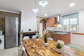 Eine moderne Küche mit Holztisch, Edelstahlgeräten und einer Wand mit Steinverkleidung.