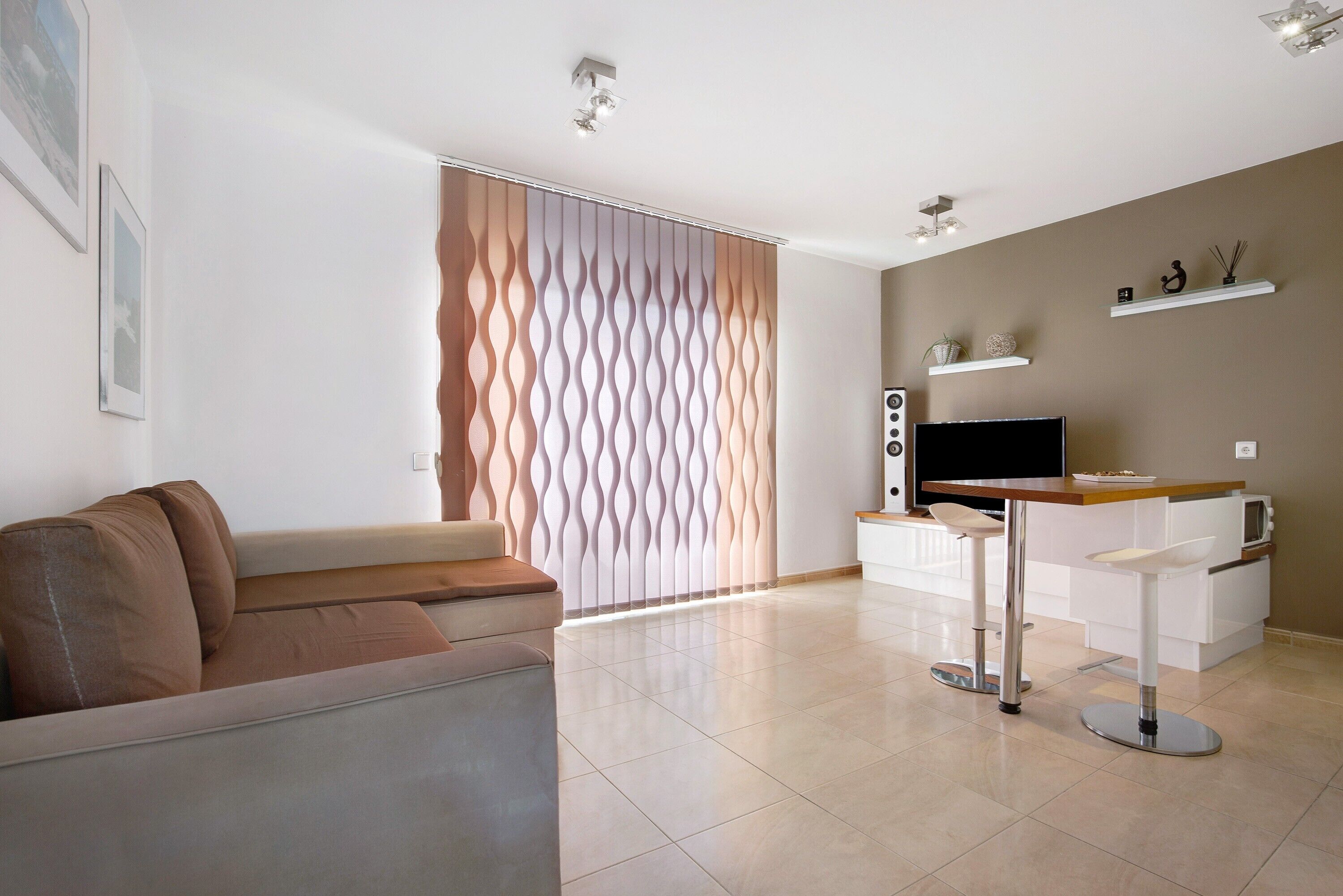 A modern living room with a sofa, a TV, a coffee table, and a decorative wall panel.