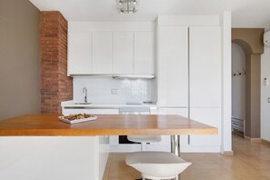 Una cocina con armarios blancos, una encimera de madera y una pared de ladrillo.